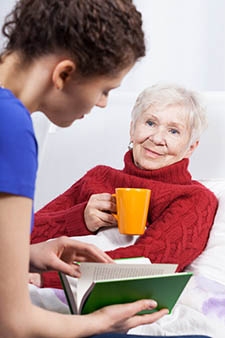 Young caregiver reading to older lady