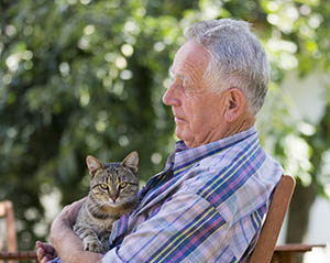 Image of older man holding his cat while sitting on bench