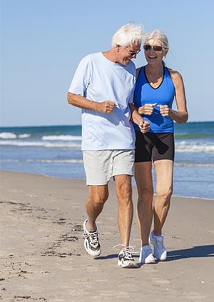 Image of older couple jogging on beach