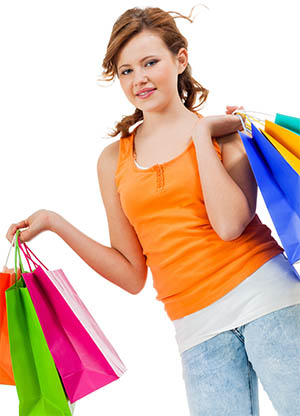 Image of young shopaholic with her hands full of brightly colored shopping bags